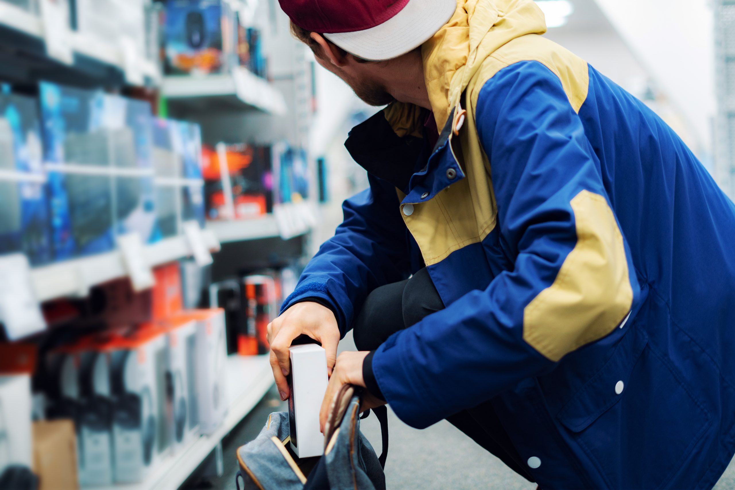 close up the consumer thief’s hands putting the new gadget in the pocket in the store Person committing retail theft